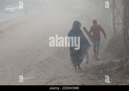 Les gens marchent sur une route poussiéreuse très fréquentée à Dhaka, au Bangladesh, le 25 novembre 2020. L'état de l'air de la ville de Dhaka s'aggrave jour après jour en cas d'alarme Banque D'Images