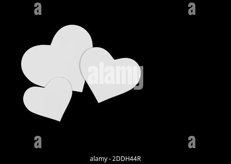 trois cœurs de papier de différentes tailles sur fond noir Banque D'Images