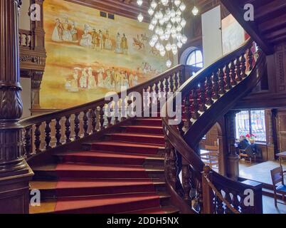 Escaliers qui mènent vers le haut ou dans un château de Moszna avec des rampes en bois et un lustre. Banque D'Images