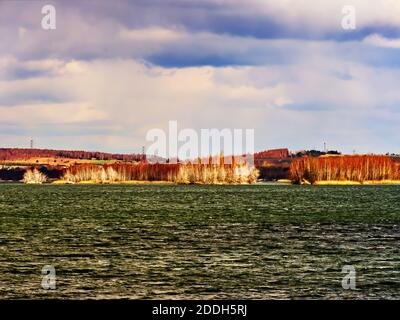 Paysage au lac avec eau verte et ciel bleu avec une terre à l'horizon. Banque D'Images