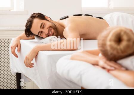 Couple profitant d'un massage de pierre couché et relaxant au salon de spa Banque D'Images
