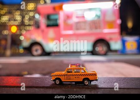 Un cliché sélectif d'un modèle de taxi classique jaune garé par le camion de glace rose dans une rue À New York au crépuscule Banque D'Images