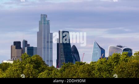 vue lointaine des grands bâtiments de la City de Londres au-delà d'une ligne d'arbres Banque D'Images