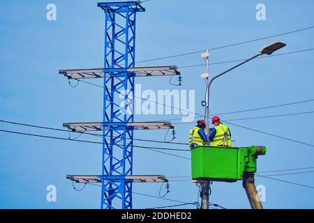 Les électriciens de sexe masculin réparent une tour de puissance située à une hauteur élevée altitude Banque D'Images