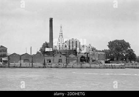 Royaume-Uni, Londres, Docklands, Isle of Dogs, début 1974. Vue depuis Greenwich Pier sur la Tamise. Cumberland Oil Mills, Luralda Wharf (Saunders Ness Rd). Christ Église derrière. L'entreprise a été créée en 1857 pour la production d'huile de lin et de tourteaux d'huile. Banque D'Images