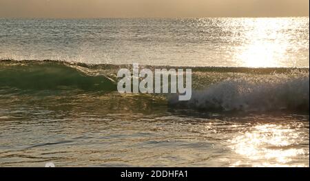 Vagues se dirigeant vers la plage comme la lumière du soleil frappe le eau Banque D'Images