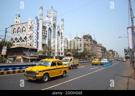 Kolkata, Inde - mars 2014 : ambassadeur de taxi jaune classique dans la rue en face de la mosquée de Calcutta. Route de circulation indienne Banque D'Images