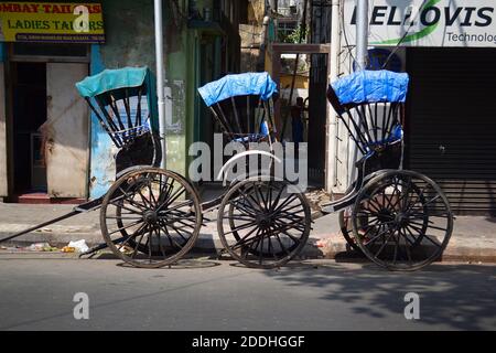 Kolkata, Inde - Mars, 2014: Trois chariots de pousse-pousse tirés à la main vides garés le long de la route dans la rue dans la ville historique de Calcutta Banque D'Images