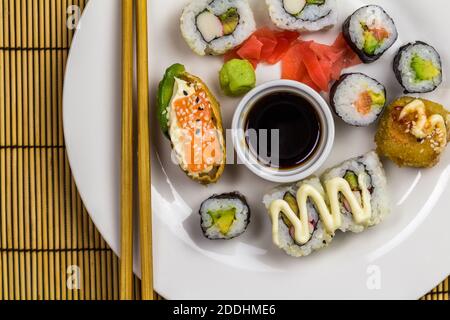 Plateau de sushis avec assortiment de petits pains à sushis avec baguettes, gingembre et wasabi - vue de dessus avec espace pour les copies Banque D'Images