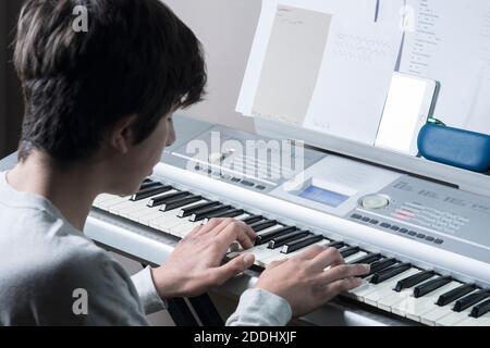 Un adolescent joue du piano à clavier électronique Banque D'Images