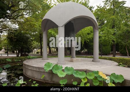 Vue horizontale de la cloche de la paix dans l'étang avec Oga Lotus, Peace Memorial Park, Hiroshima, Japon Banque D'Images