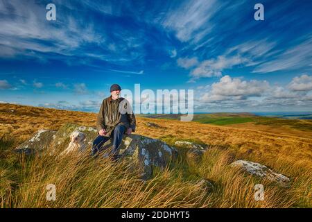 Homme dans ses années 70 se reposant en marchant dans les collines de Preseli, Pembrokeshire, pays de Galles Banque D'Images