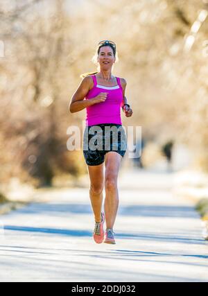 Attrayant; d'âge moyen; femme en forme qui court sur un sentier pavé; Salida; Colorado; États-Unis Banque D'Images
