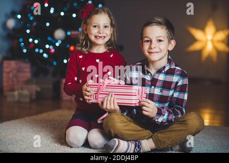 Deux enfants heureux dans nouvel an avec présente près de Nouvel An des arbres à la maison Banque D'Images