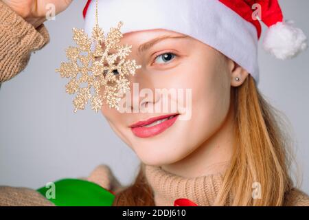 Une belle dame tient un flocon de neige doré sur un fond blanc. Banque D'Images