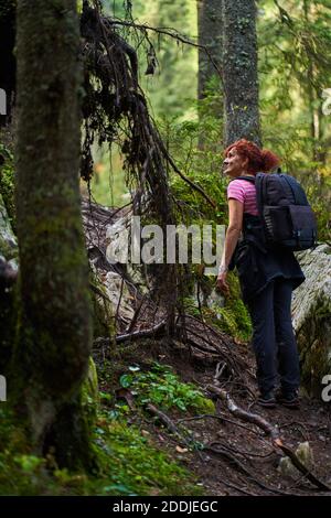 Femme active avec sac à dos randonnée sur un sentier à travers le forêt Banque D'Images