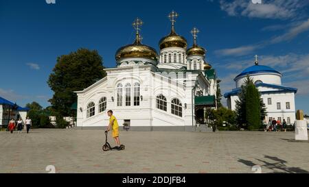 Cathédrale Sainte-Trinité et cathédrale de la mère de Dieu de Géorgie, monastère de Raifa. nr. Kazan. Russie. Un garçon fait des promenades en scooter devant le buil de l'église Banque D'Images