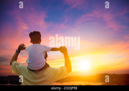 père donnant son fils pigegyback sur ses épaules et regardant le coucher du soleil Banque D'Images