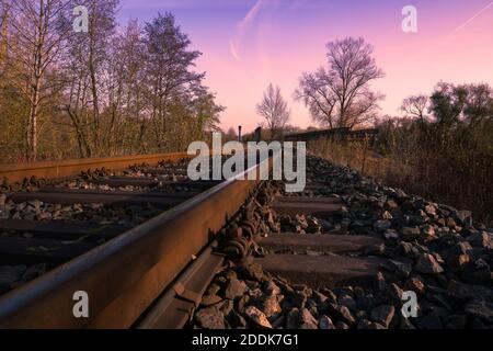 Chemin de fer sous le ciel violet de coucher de soleil en automne, près de la perspective du sol Banque D'Images