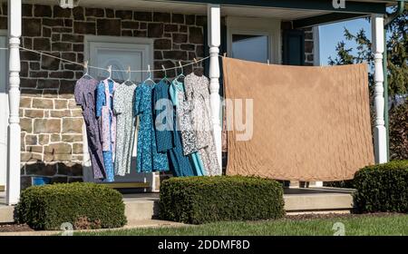 Les robes pendent sur la corde à linge pendant qu'elles sèchent sur le porche avant Corde à linge sur la ferme Mennonte Banque D'Images