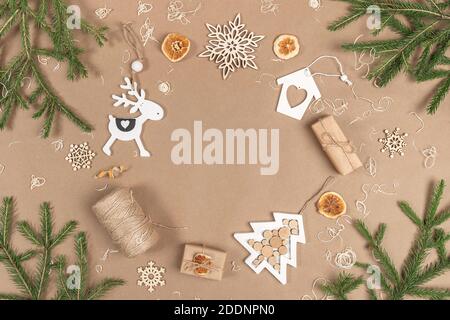 COMPOSITION NOËL ou nouvel an. Cadre, bordure faite de boîtes, ficelle, décoration en bois, oranges séchées et branches d'épinette sur fond beige artisanal. Conc Banque D'Images
