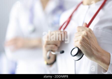 Médecin cardiologue tenant le stéthoscope rouge dans le bureau de la clinique de proximité Banque D'Images