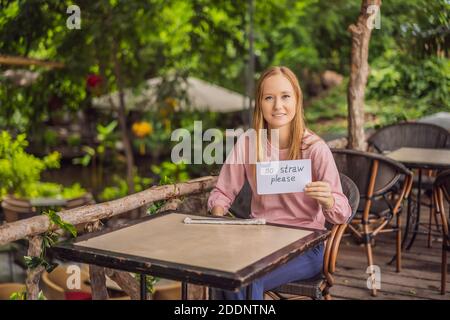 Une jeune femme dans un café montre un panneau - pas de pailles s'il vous plaît. Pas de plastique. Problème de protection de l'environnement mondial Banque D'Images