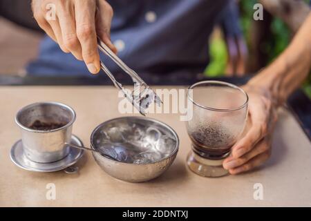 Homme caucasien et café vietnamien traditionnel infusé par goutte d'eau d'un filtre phin Banque D'Images