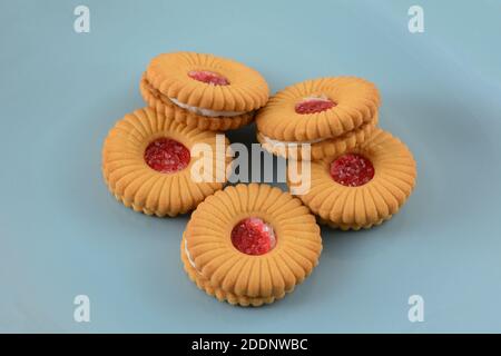 Biscuits sandwich à la crème de fraise avec confiture de fraise sur le dessus sur la plaque bleue Banque D'Images