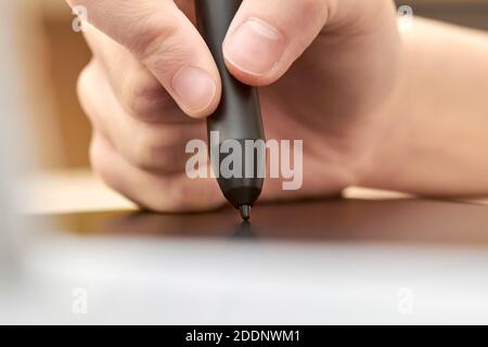 Fille tire sur une tablette graphique avec un stylo. Gros plan, mise au point sélective Banque D'Images