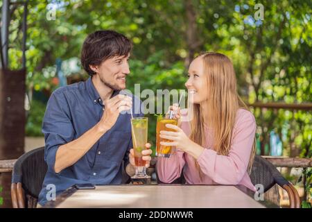 Un couple respectueux de l'environnement utilisant de la paille en acier inoxydable réutilisable pour boire thé aux fruits Banque D'Images