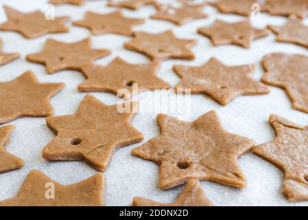 pâte à biscuits maison de pain d'épice coupée en étoiles préparées à l'être cuit sur du papier parchemin Banque D'Images