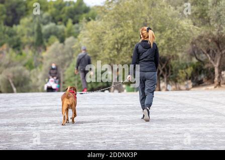 Athènes Grèce. 22 novembre 2020. Jeune femme avec un masque de protection du visage COVID 19 marchant avec un chien au centre-ville, rue Areopagitou. Coronavirus Banque D'Images