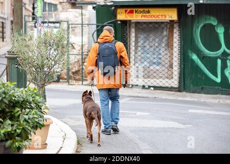 Athènes Grèce. 22 novembre 2020. Homme avec un masque de protection du visage COVID 19 marchant avec un chien au centre-ville, région de Monastiraki. Verrouillage du coronavirus d Banque D'Images