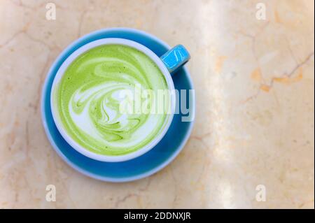 latte à thé vert matcha avec un motif de mousse de lait dans une tasse en céramique bleue sur la table Banque D'Images