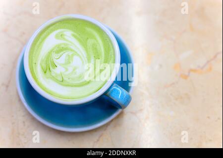 latte à thé vert matcha avec un motif de mousse de lait dans une tasse en céramique bleue sur la table Banque D'Images