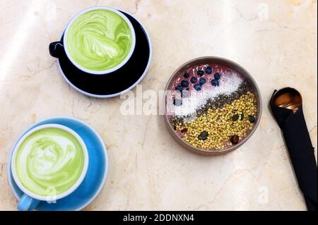 bol à smoothie, aliments crus et tasse de thé vert au lait de matcha sur la table Banque D'Images