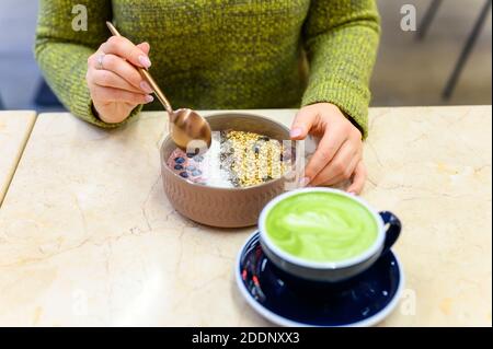 Saladier à smoothie d'aliments crus et latte matcha tasse de thé vert sur la table et une femme prête à manger Banque D'Images