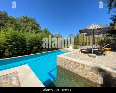 Côté piscine calme et confortable avec statue de Bouddha et arbres cultivés. Piscine au centre d'une forêt entourée d'arbres verts en pierre naturelle. Banque D'Images