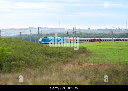 Anapa, Russie - 09.26.2020: Un train de chemin de fer russe se déplace sur les rails entre les champs et les prairies Banque D'Images