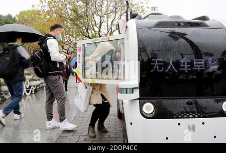 Shanghai, Chine. 26 novembre 2020. Un client prend de la nourriture dans une voiture de restauration sans pilote à Shanghai, dans l'est de la Chine, le 26 novembre 2020. Des voitures de restauration sans pilote, contrôlées à distance, vendent de la nourriture aux gens de ZJ Science City à Shanghai. Les clients peuvent faire un geste pour arrêter la voiture, sélectionner des marchandises à l'écran et payer en scannant le code QR. Credit: Fang Zhe/Xinhua/Alay Live News Banque D'Images