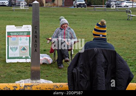 (201126) -- SURREY, le 26 novembre 2020 (Xinhua) -- les gens se rencontrent dans le parc national historique de Peace Arch, où une petite partie de celui-ci est délimitée le long de la frontière canado-américaine, pendant la fête de Thanksgiving, le 25 novembre 2020. La frontière américaine et canadienne est restée fermée au trafic non essentiel depuis mars en raison de la COVID-19. Des amis et des parents canadiens et américains se rencontrent pendant la semaine américaine de Thanksgiving le long de la frontière, bien qu'ils soient séparés par la fermeture de la frontière. Le parc national historique de Peace Arch est à cheval sur la frontière et permet aux personnes des deux nationalités de se rencontrer pendant la pandémie de bo Banque D'Images