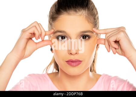 portrait de jeune belle femme, pinçant ses rides d'oeil sur fond blanc Banque D'Images