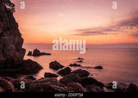 Les rochers de la plage de Golfet entourés par la mer pendant un beau coucher de soleil à Calella de Palafrugell, Espagne Banque D'Images