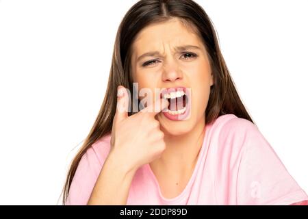 Jeune femme avec un mal de dents fort pointant sur sa dent bacille blanc Banque D'Images