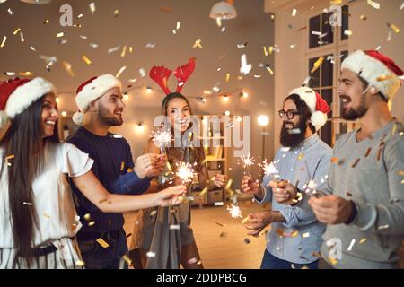 Groupe de jeunes amis souriants éclairant des éclairs lors de la fête de Noël Banque D'Images