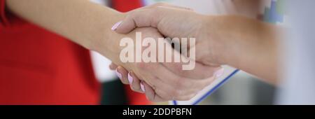 Poignée de main des femmes d'affaires en costume avec des papiers dans le bureau gros plan Banque D'Images