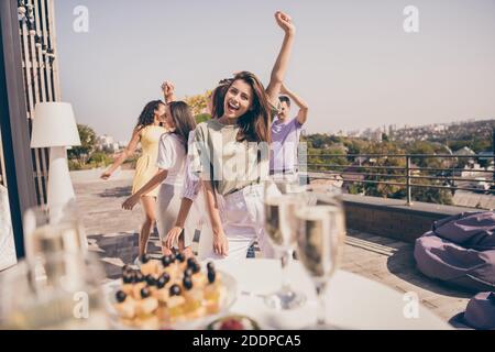 Photo de sympathiques jolis gars ont des repas dansants amusants boissons sur la table de fête sur la terrasse du toit à l'extérieur Banque D'Images