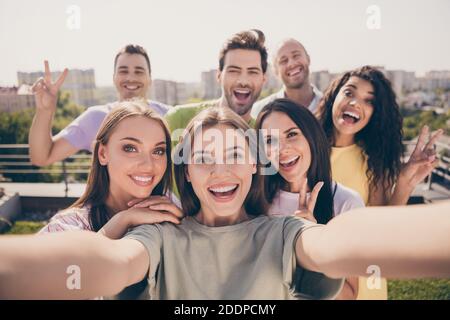 Photo de filles gaies les gars faisant selfie show v-sign faites une fête sur la terrasse du toit à l'extérieur Banque D'Images