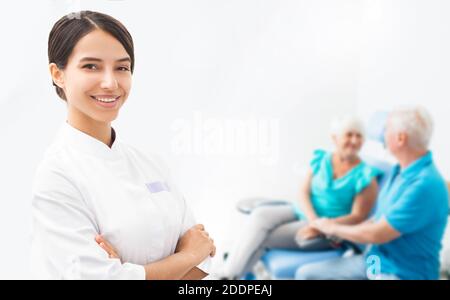 Femme souriante médecin, les patients âgés s'assoient ensemble derrière elle. Portrait d'un médecin, sur le fond des patients âgés Banque D'Images